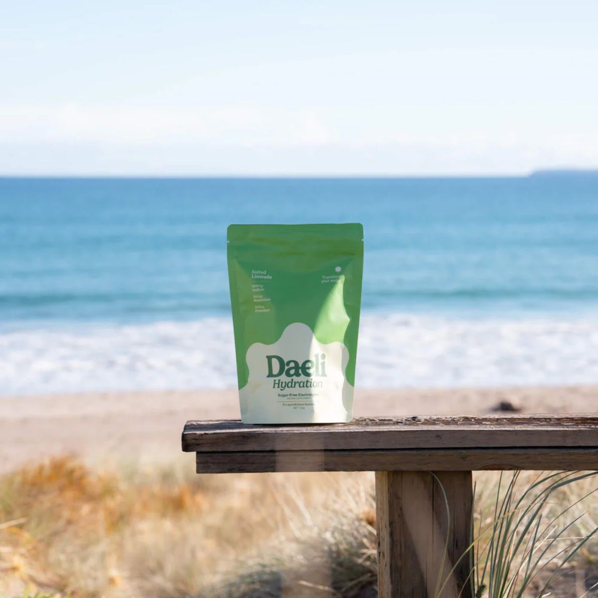 Green package labeled 'Daeli' on a wooden bench with ocean view