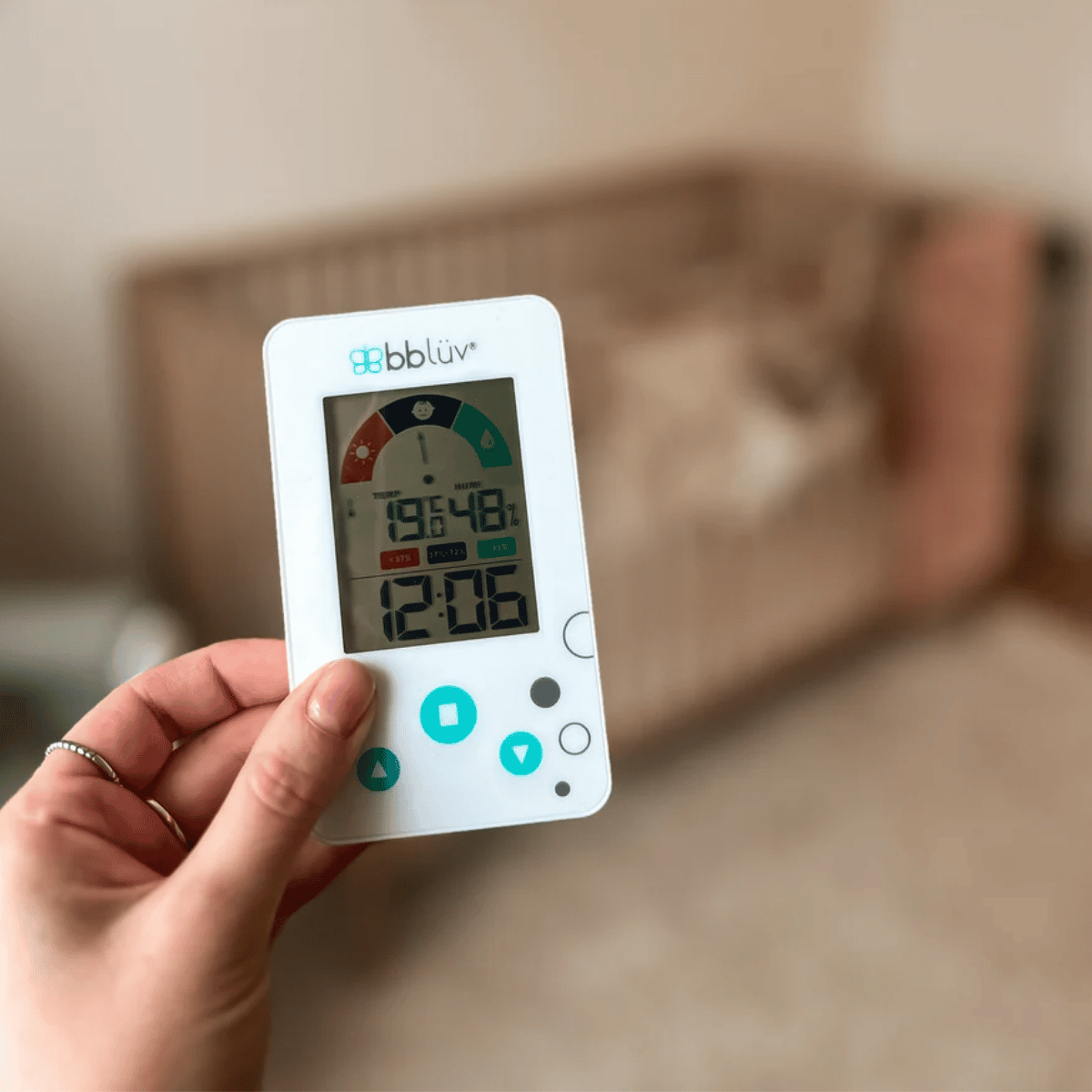 Hand holding a digital thermometer with a blurred background