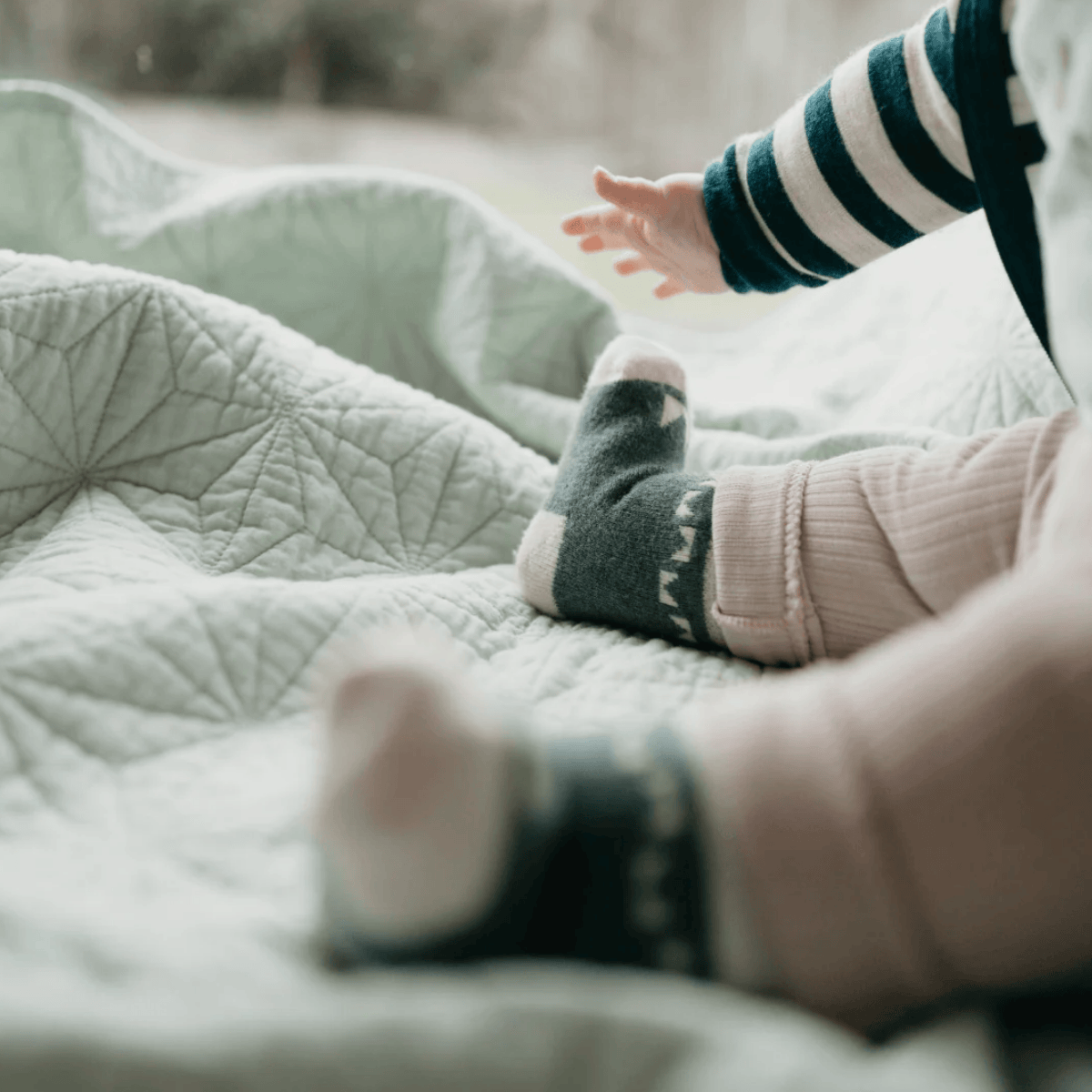 Baby's feet and legs with striped socks on a soft surface