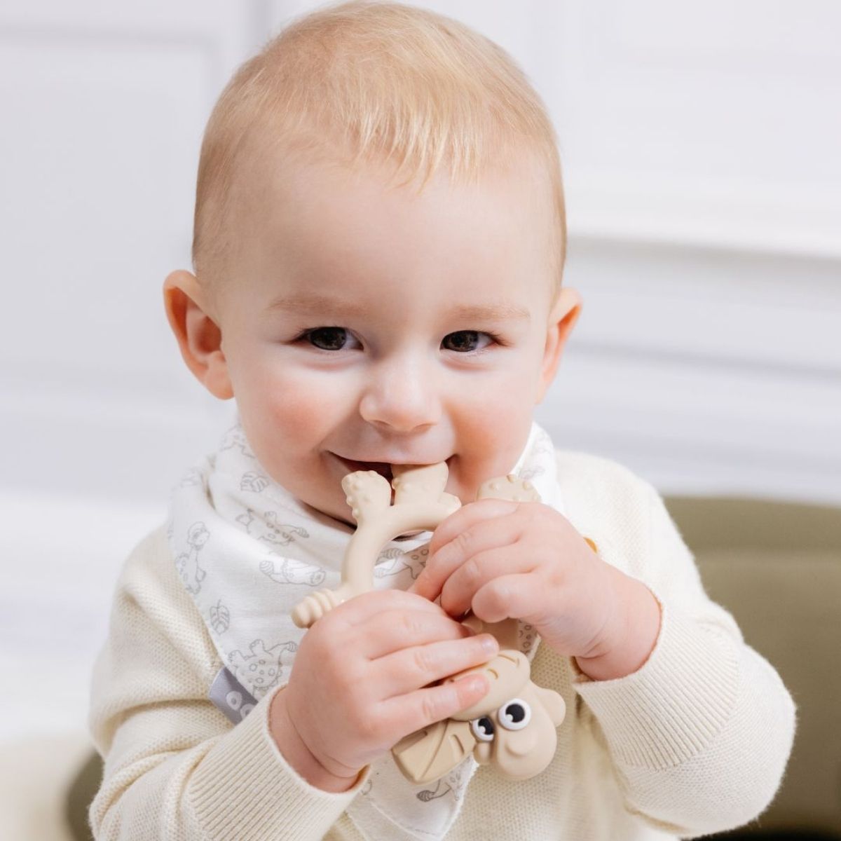 Teething baby holding onto multisensory teether, Dotty.