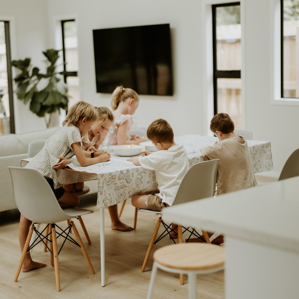 A group of children colouring their tablecloth at the table.