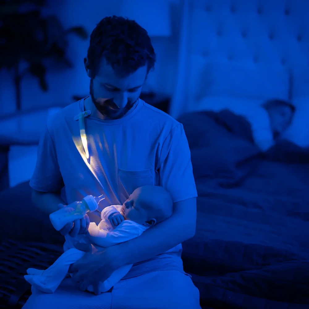 Dad wearing the LatchLight whilst feeding the baby during the night.
