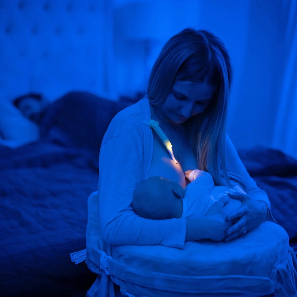 Mum breastfeeding her baby whilst wearing the LatchLight to help her see whilst not disrupting the baby or partner.