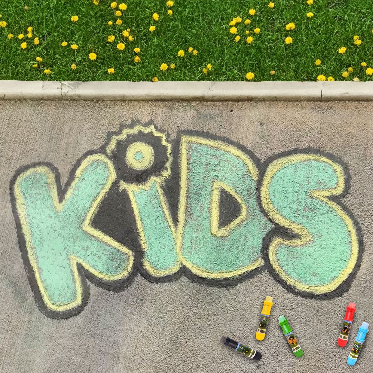 Chalk drawing of 'KIDS' on pavement with sidewalk John Deere chalk next to it.