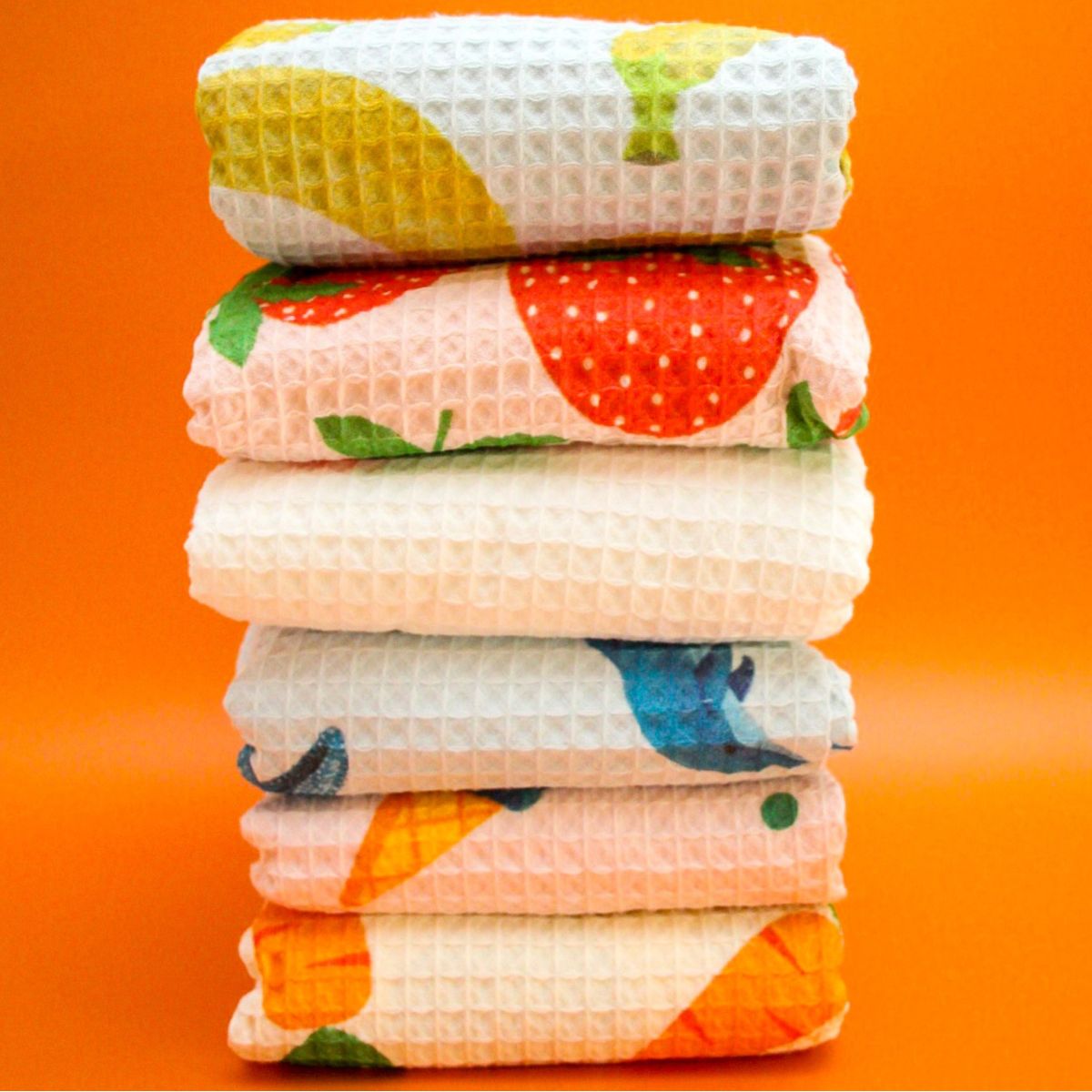 Stack of colourful folded towels on an orange background
