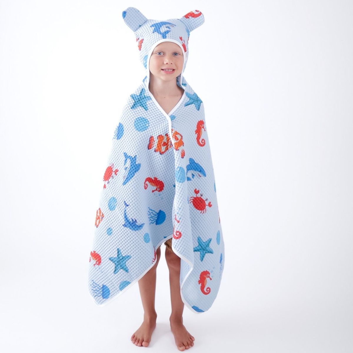Child wearing a hooded towel with animal patterns on a white background