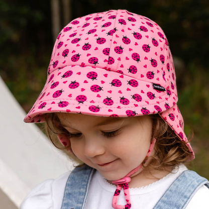 Child wearing a pink sun hat with ladybug pattern outdoors