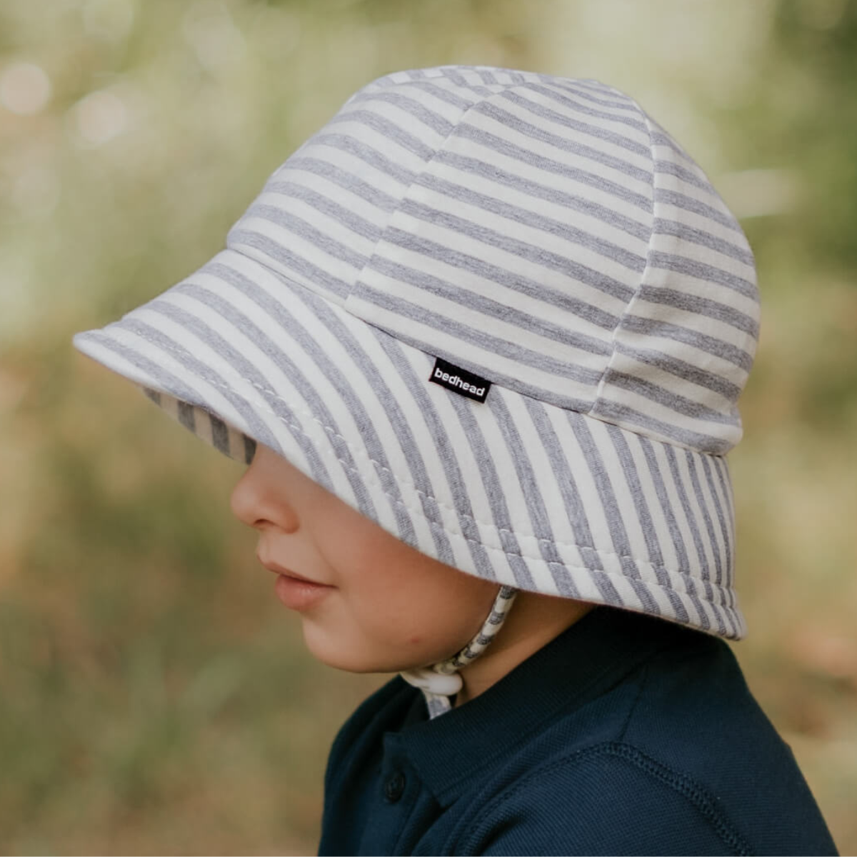 Child wearing a striped sun hat with a blurred natural background