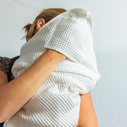 Baby wearing a white textured toddy towel garment against a plain background