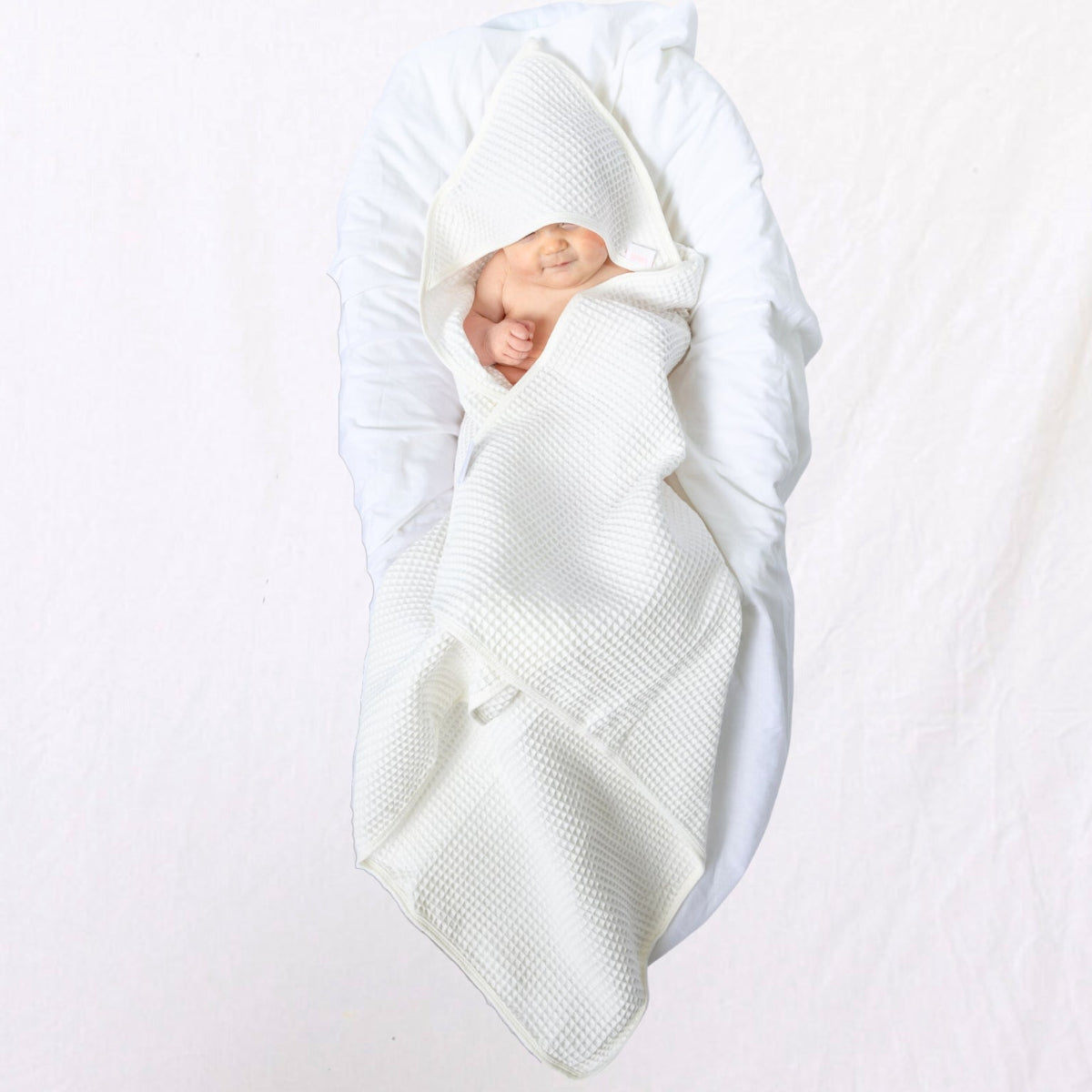Newborn baby wrapped in a white blanket on a light gray background