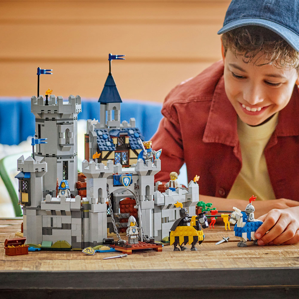 Child playing with a LEGO castle set on a wooden table