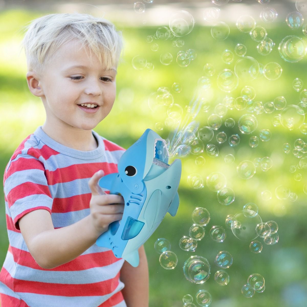 Child playing with a bubble gun in a park