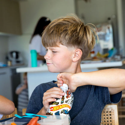 Child holding a Hot Wheels sinchie bottle in a kitchen setting