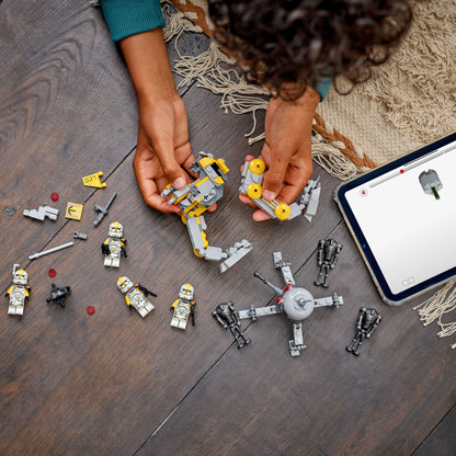 Child playing with toy building blocks on a wooden floor next to a tablet.