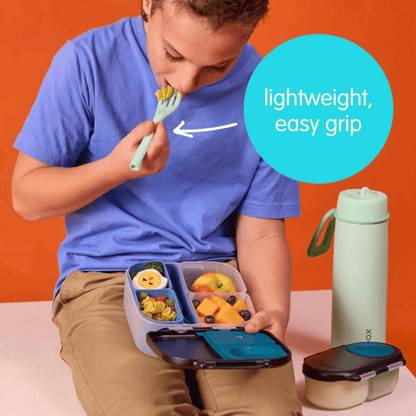 Child eating from a bento box with a water bottle and snack container on an orange background