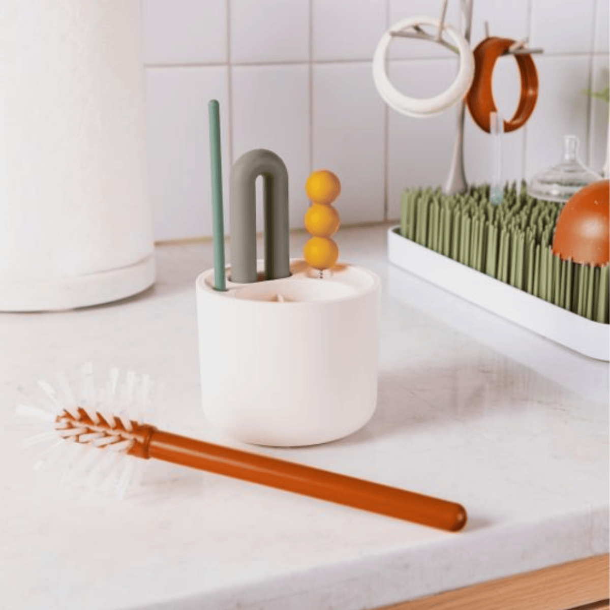 Set of colorful cleaning brushes in a white holder on a kitchen counter.