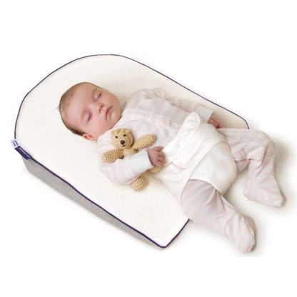 Baby sleeping in a white crib with a teddy bear, on a white background