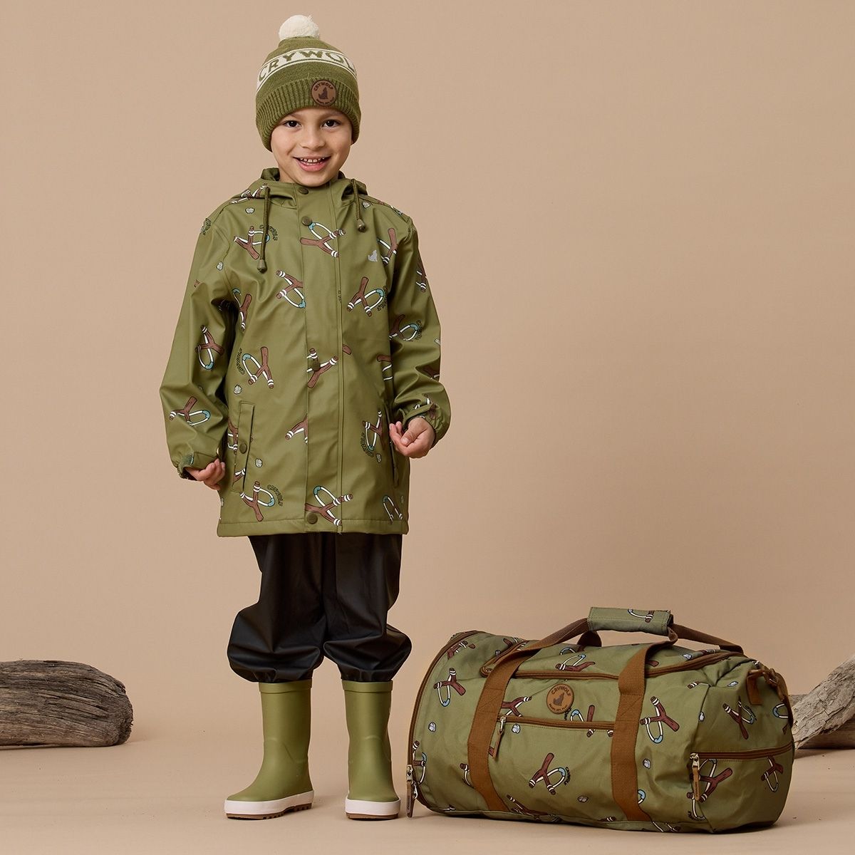 A boy with his Crywolf green packable duffle bag and Alpine Beanie.
