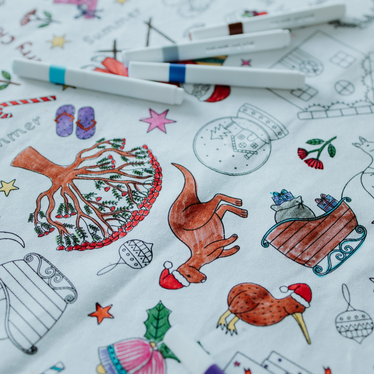 Coloring table cloth with Christmas-themed illustrations and coloring tools.
