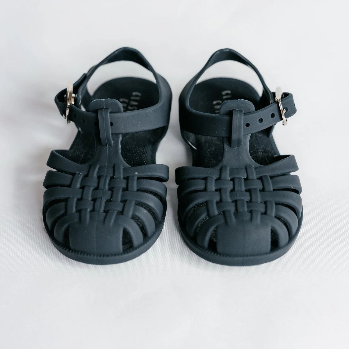 Pair of navy blue sandals with woven design on a white background