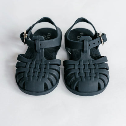 Pair of navy blue sandals with woven design on a white background