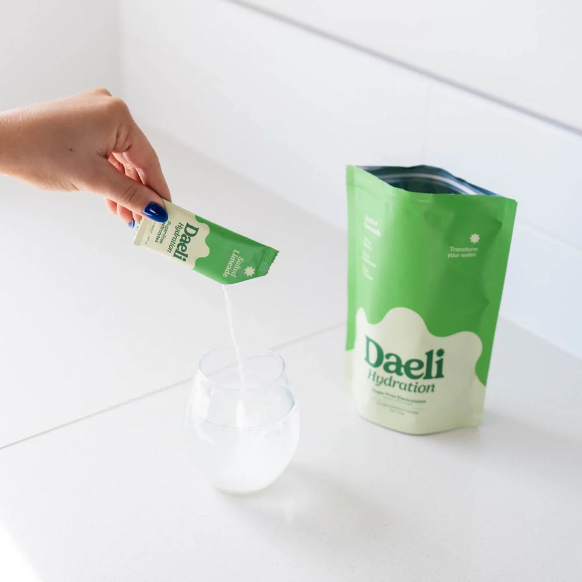 Person holding a green Daeli packaging over a white container on a white background
