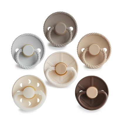 Six baby pacifiers in assorted neutral colors including gray, beige, cream, and brown, arranged on a clean white background.
