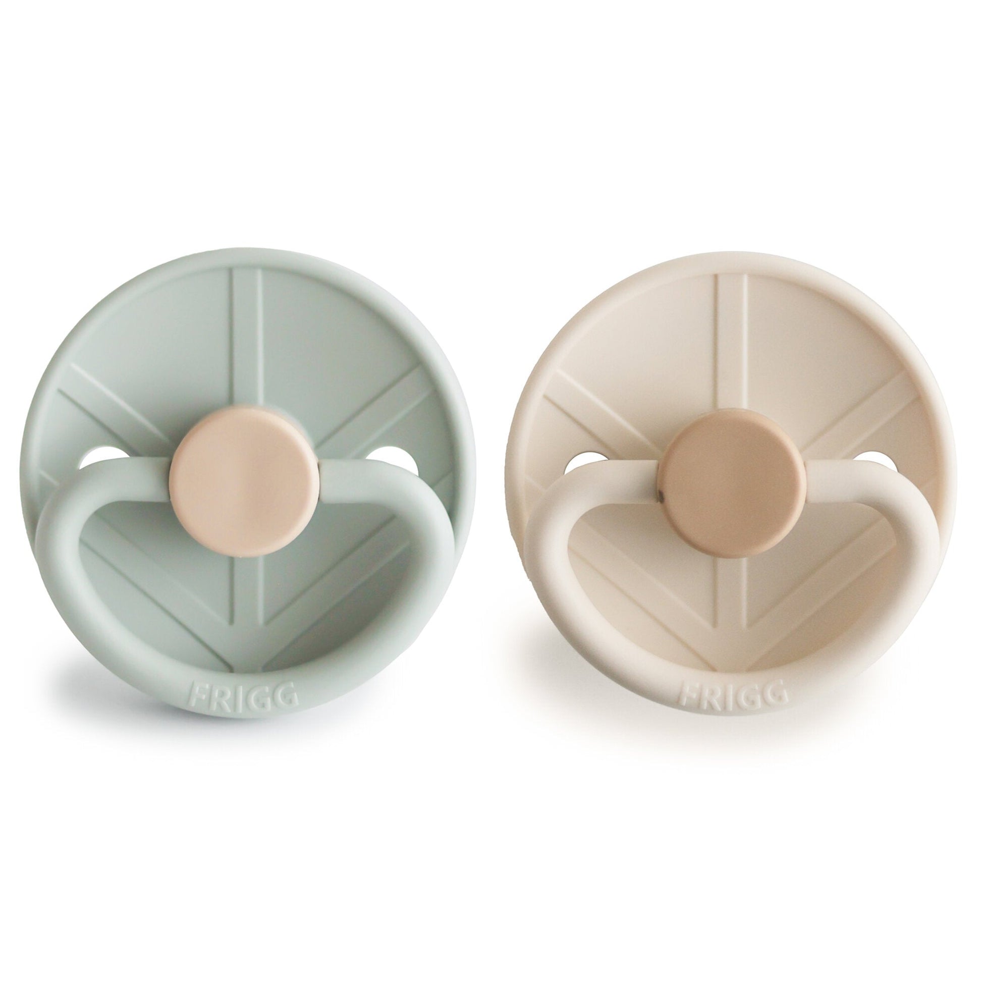 Two pacifiers, one green and one beige, with 'Frigg' branding on a white background.