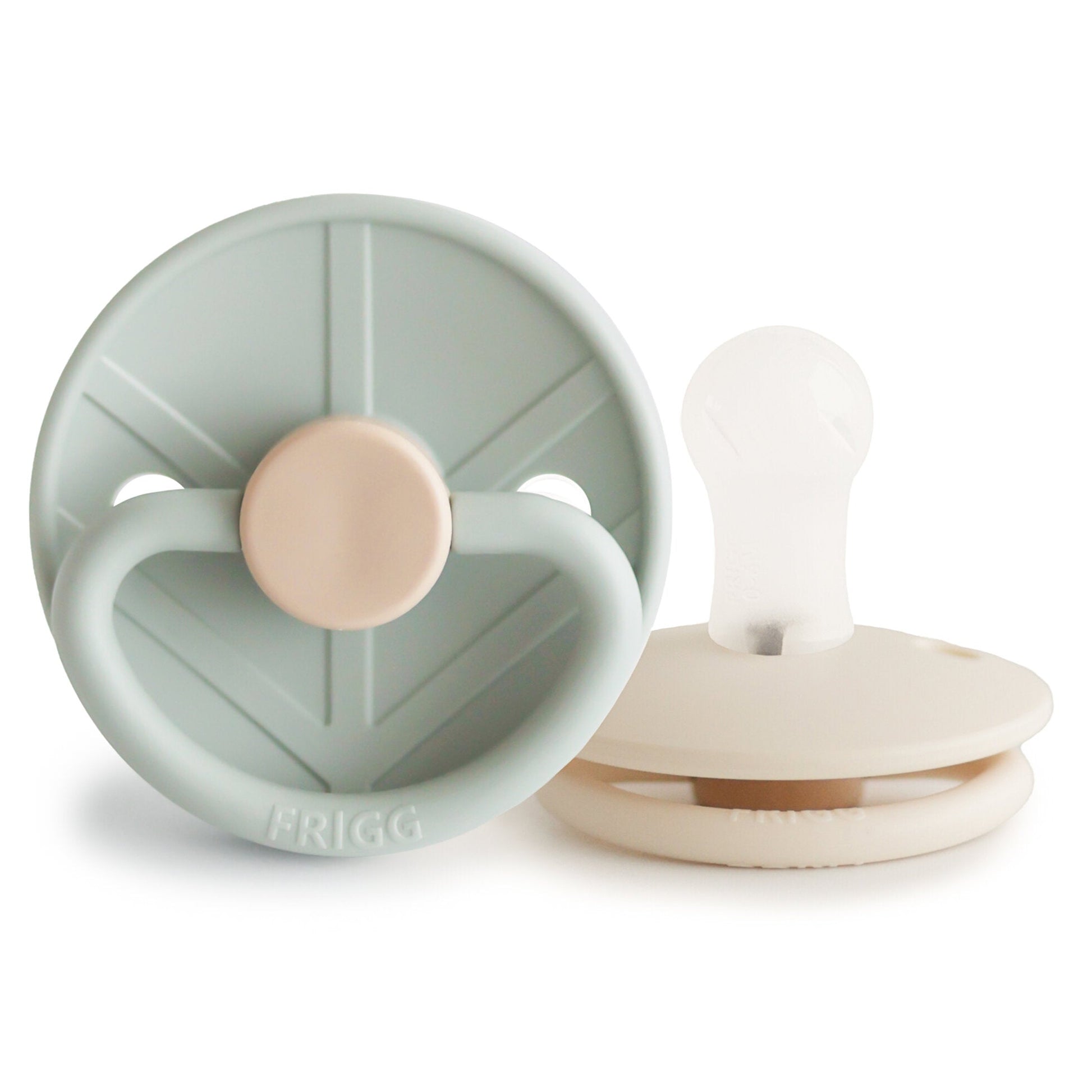 Two baby pacifiers, one green and one beige, on a white background with 'Frigg' branding.
