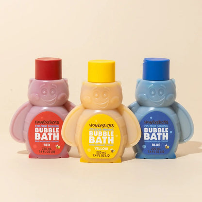 Three bottles of Honeysticks bubble bath in red, yellow, and blue on a beige background