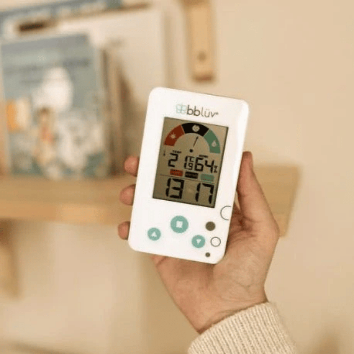 Hand holding a digital thermometer with bbluv branding, displaying temperature and humidity readings.
