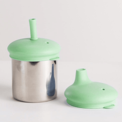 Green silicone lid on a metal smoothie container against a light gray background