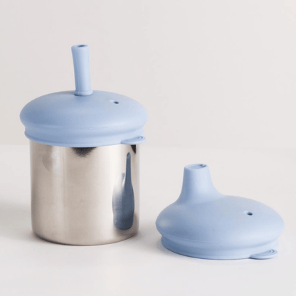Stainless steel container with blue silicone lid and straw on a light gray background