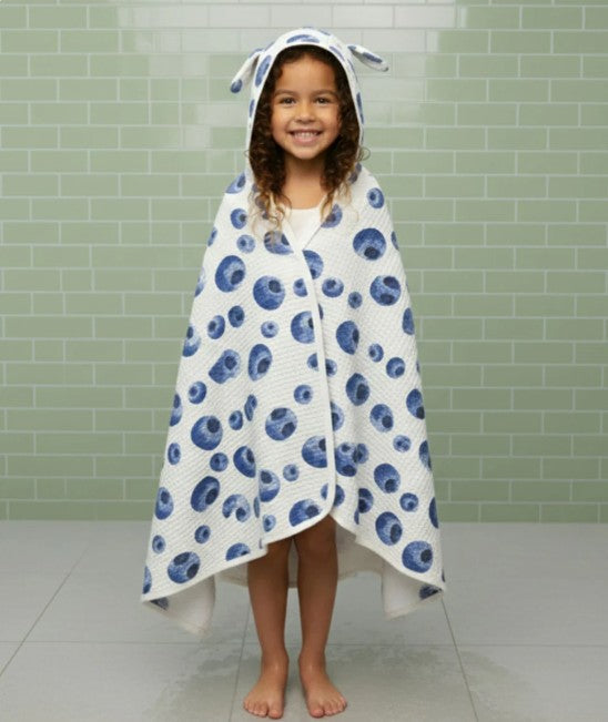 Child wearing a blue and white patterned hooded towel in a bathroom.