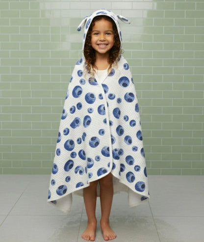 Child wearing a blue and white patterned hooded towel in a bathroom.