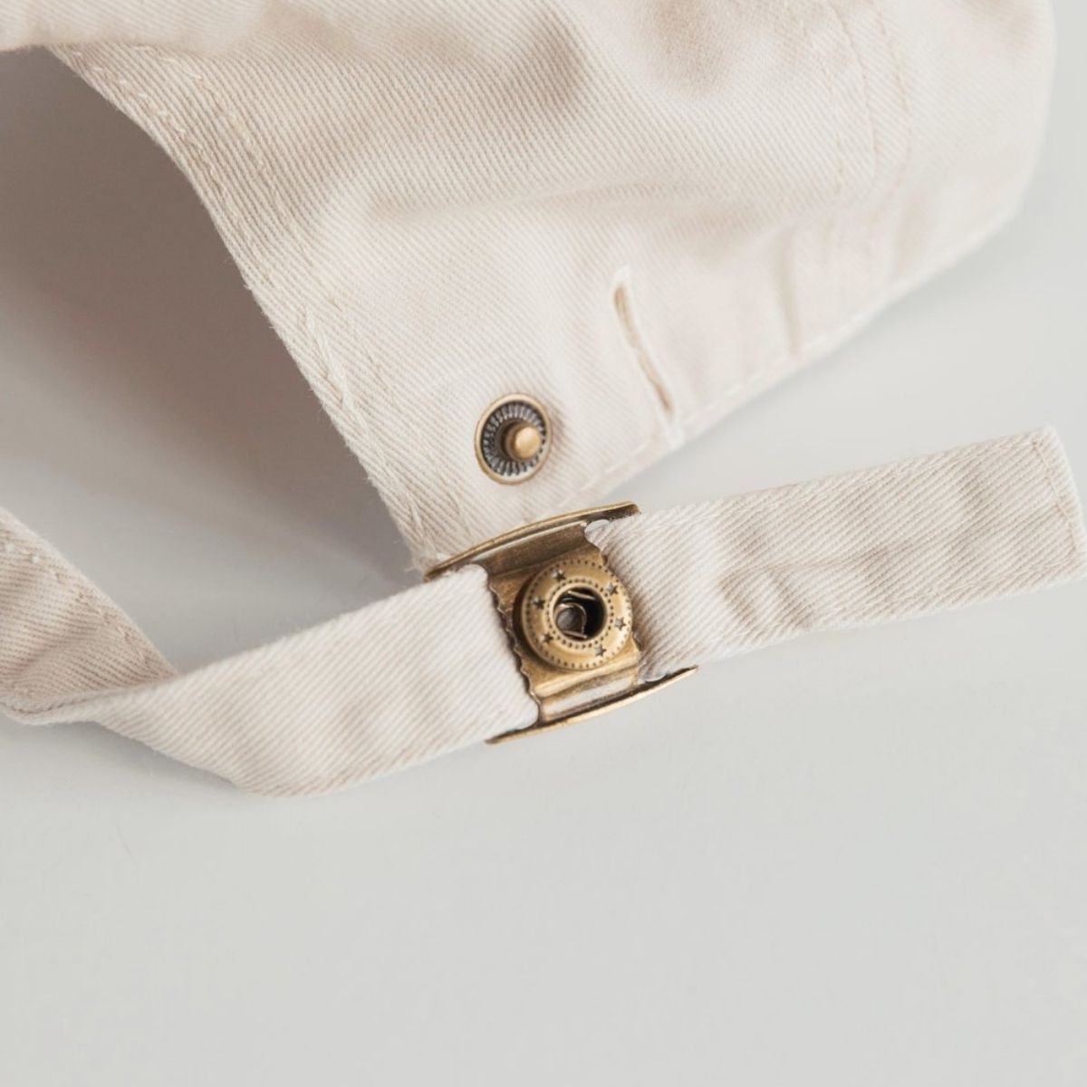 The clasp of the mum club hat. Gold detailing.