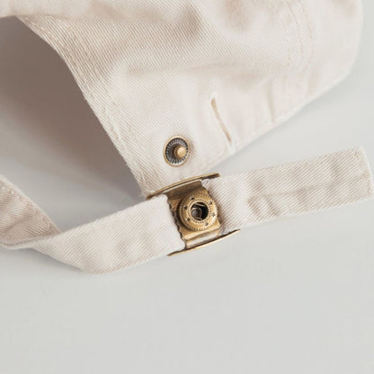 The clasp of the mum club hat. Gold detailing.