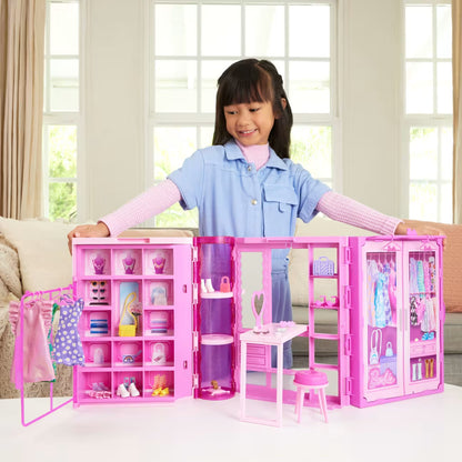 Child playing with a pink dollhouse and accessories in a bright room.