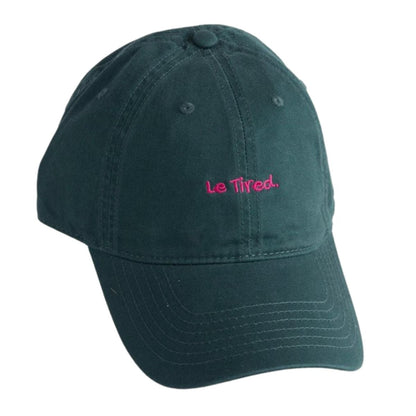 A dark green hat with the pink words on it saying le tired'.