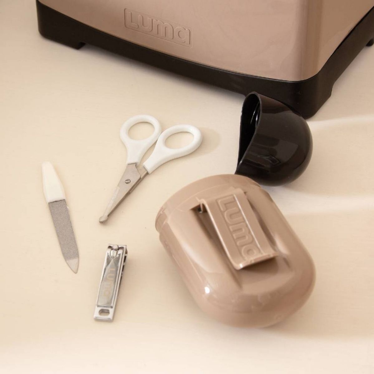 The Luma manicure set on a table showing the file, clippers and scissors. Has a handy clip on the back to clip onto a baby bag.