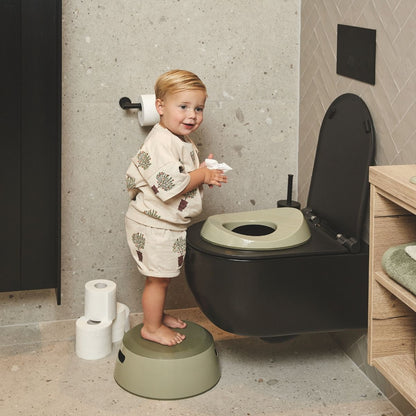 Child using a toilet with an  olive green step stool in a bathroom setting.