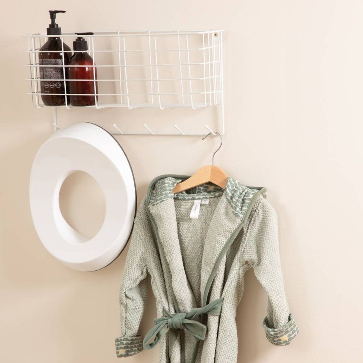 The Luma toilet seat hanging next to a Green robe in the bathroom.